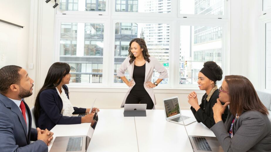 Diverse team engaged in a business meeting with laptops in a modern office setting.