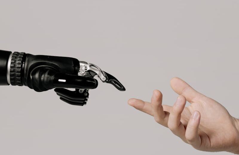 A human hand reaching to touch a bionic prosthetic hand on a white background.